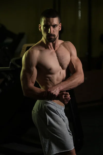 Homem muscular flexionando músculos no ginásio — Fotografia de Stock