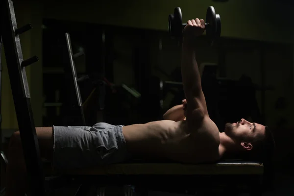 Hombre en el gimnasio ejercitando tríceps con mancuerna — Foto de Stock