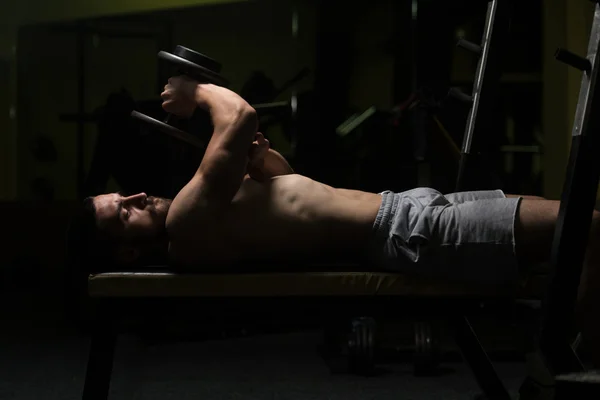 Triceps cvičení s činka v temné místnosti — Stock fotografie