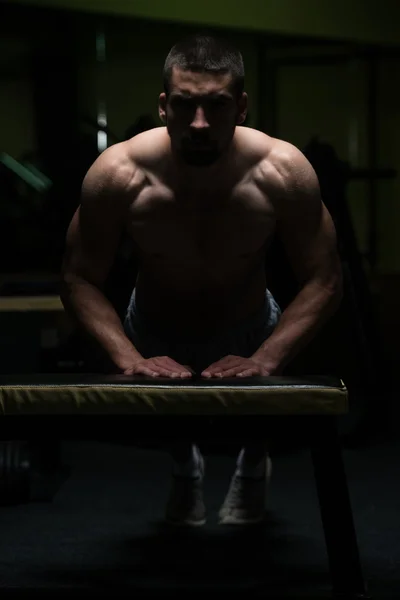 Push-ups en el banco en una habitación oscura — Foto de Stock