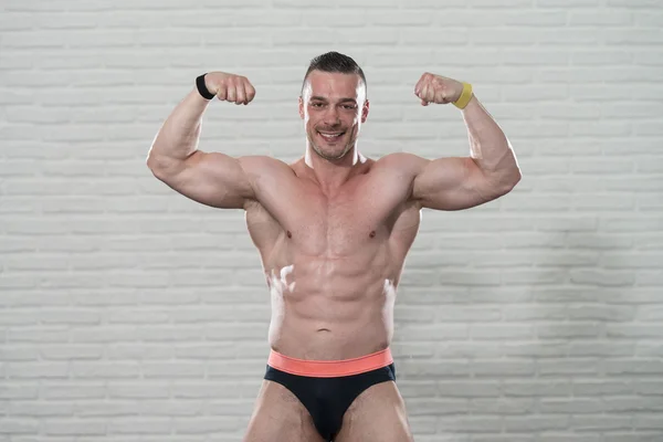 Muscular Man Flexing Muscles On White Bricks Background — Stock Photo, Image