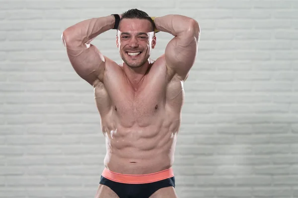 Gespierde Man buigen spieren op witte bakstenen achtergrond — Stockfoto