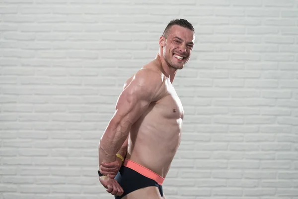 Muskulöser männlicher Körper isoliert auf weißem Backstein Hintergrund — Stockfoto