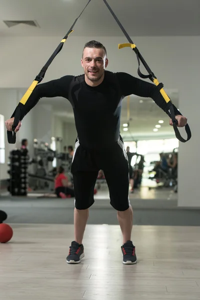 Treinamento de homem atraente jovem com correias Trx Fitness — Fotografia de Stock