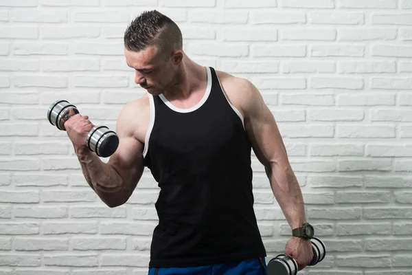 Man uitoefening Biceps op witte bakstenen achtergrond — Stockfoto