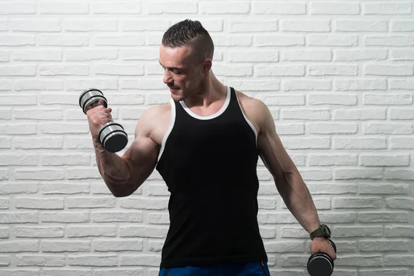 Jeune homme exercice biceps avec haltères — Photo