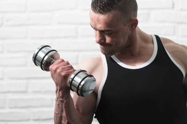 Hombre ejercitando bíceps sobre fondo de ladrillos blancos —  Fotos de Stock