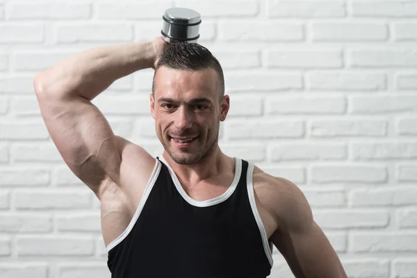 Triceps training met Dumbbells op witte bakstenen achtergrond — Stockfoto