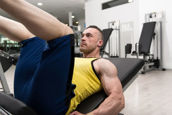 Hombre en el gimnasio en el ejercicio de la máquina — Foto de Stock