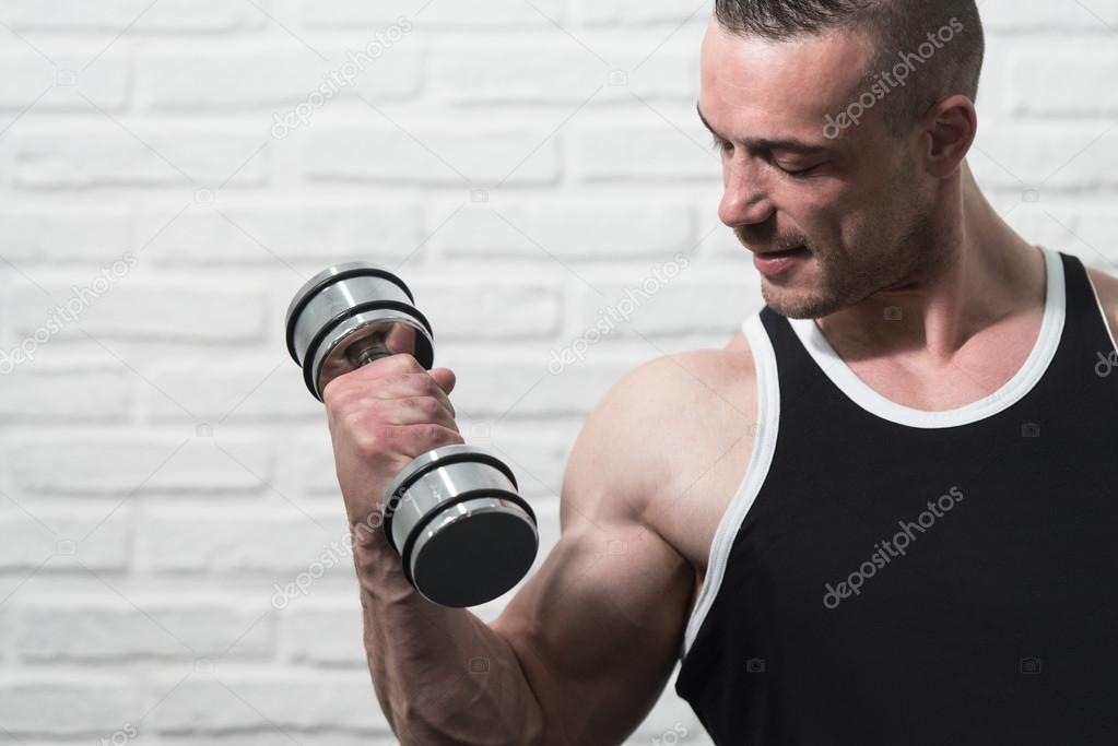 Man Exercising Biceps On White Bricks Background