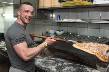 Genç koyarak Pizza fırın içine adam.