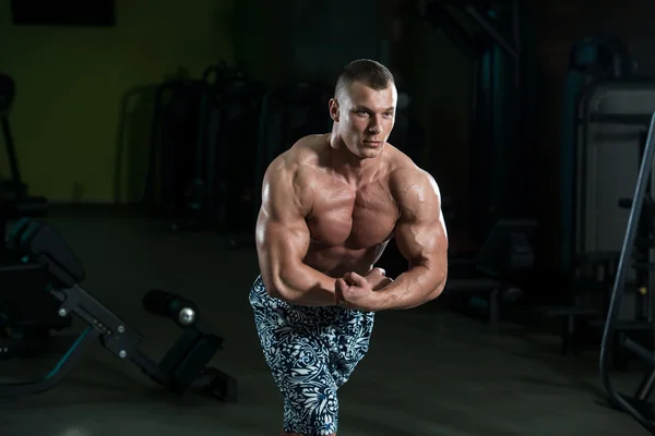 Fitness geformter Muskelmann posiert in dunkler Turnhalle — Stockfoto