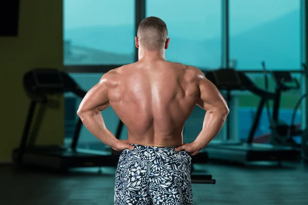 Musculoso hombre flexionando los músculos en el gimnasio — Foto de Stock