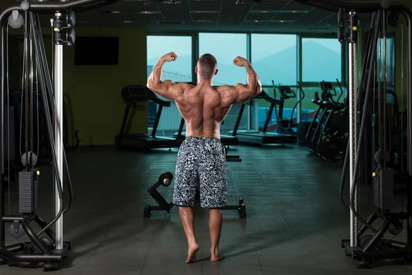 Aptidão em forma de homem do músculo posando no ginásio escuro — Fotografia de Stock