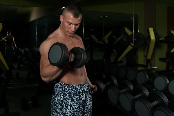 Mladý muž s činkami cvičení Biceps — Stock fotografie