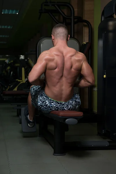 Hombre en el gimnasio haciendo ejercicio de nuevo en la máquina —  Fotos de Stock