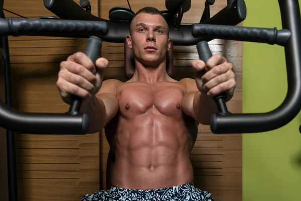 在健身房里锻炼胸部在机器上的男人 — 图库照片