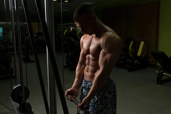 Homem muscular exercício bíceps na máquina de cabo — Fotografia de Stock