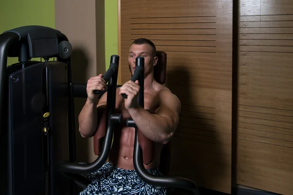 Hombre en el gimnasio ejercitando el pecho en la máquina — Foto de Stock