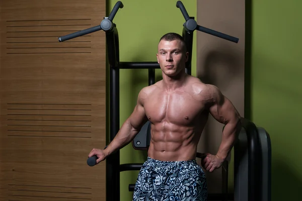 Fitness geformter Muskelmann posiert in dunkler Turnhalle — Stockfoto