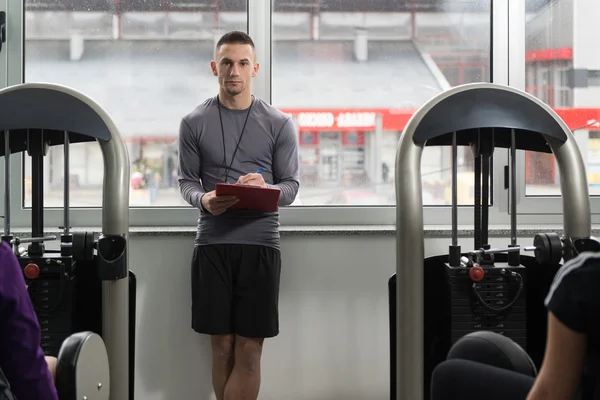 Kişisel antrenör adam bacaklar egzersiz sırasında notlar alır — Stok fotoğraf