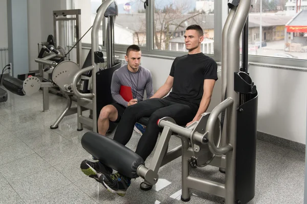 Personal Trainer toma notas enquanto homem exercitando pernas — Fotografia de Stock