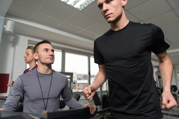 Personal Trainer e cliente in palestra su tapis roulant — Foto Stock