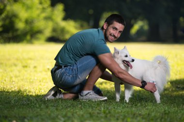 Adam parkta köpek Alman Spitz temizler