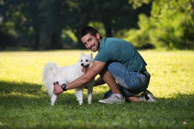 Adam parkta köpek Alman Spitz temizler