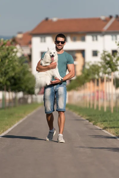 Молодой человек берет собаку на прогулку в парк — стоковое фото