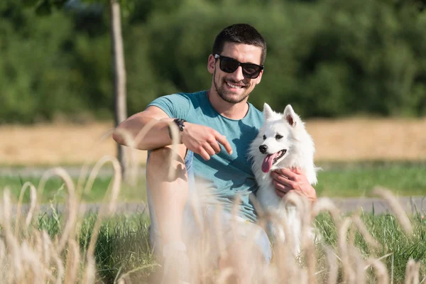 Mann und Hund sitzen auf abgeerntetem Feld — Stockfoto