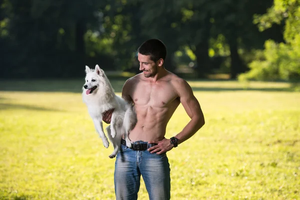 Sexy homem segurando cão alemão spitz no parque — Fotografia de Stock