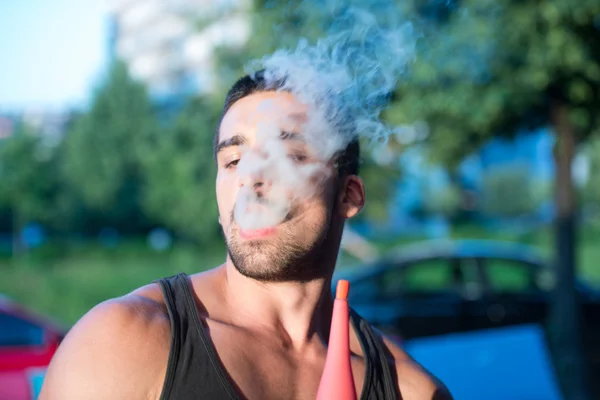 Homem exalando fumaça inalando de um narguilé — Fotografia de Stock