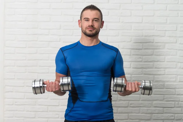 Personal Trainer Exercising Biceps On White Bricks Background — Stock Photo, Image