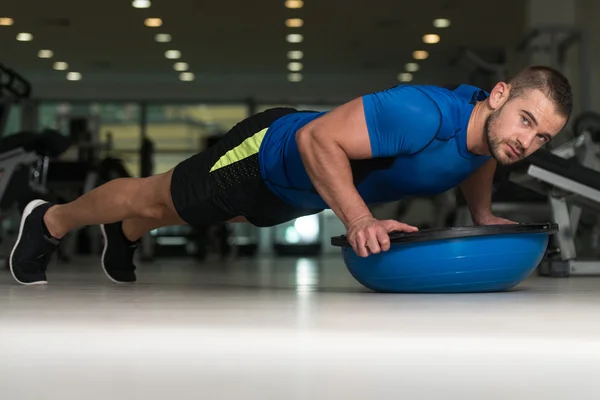 Personlig instruktör gör armhävningar med Bosu balans boll — Stockfoto