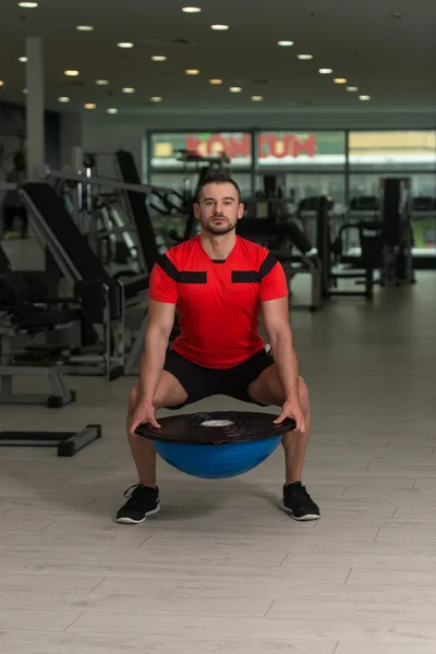 Treinador pessoal fazendo exercício na bola de equilíbrio Bosu — Fotografia de Stock