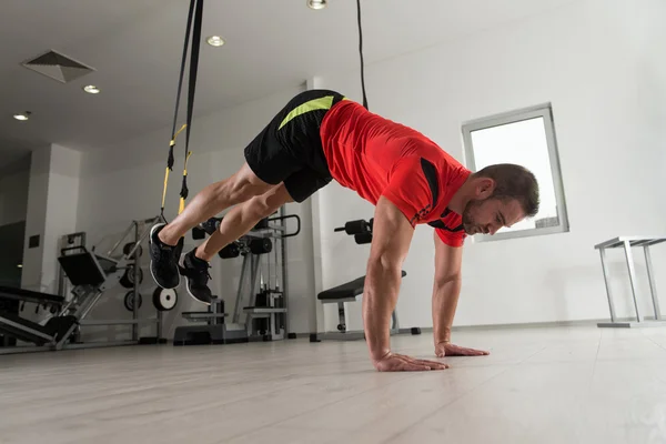 Treinamento de homem atraente jovem com correias Trx Fitness — Fotografia de Stock