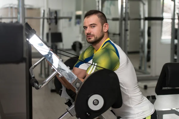 Man Training Biceps Exercises On A Machine — Stock Photo, Image