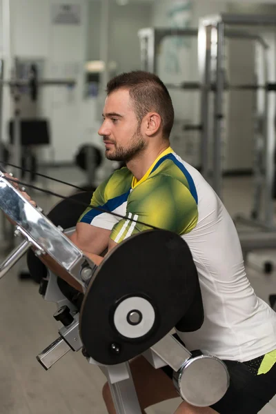 Man träna Biceps övningar på en maskin — Stockfoto