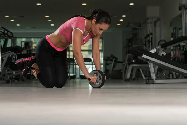 Ejercicio atractivo de la mujer con el rodillo de rueda para los abdominales —  Fotos de Stock