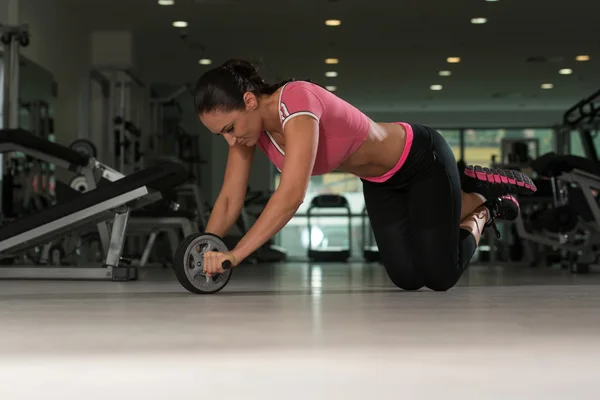 Ejercicio atractivo de la mujer con el rodillo de rueda para los abdominales — Foto de Stock