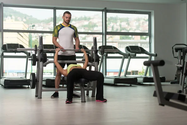 Mujer tren pecho en banco con entrenador de fitness —  Fotos de Stock