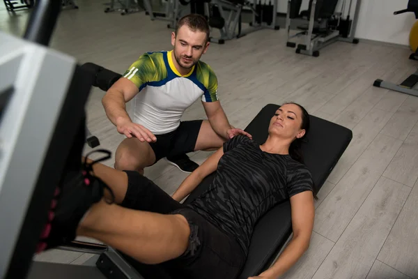 Jambes de train de femme sur la machine avec entraîneur personnel — Photo