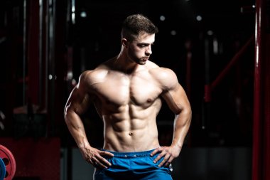Spor salonunda güçlü duran ve kaslarını esneten yakışıklı adam - kaslı atletik vücut geliştirici spor sonrası vücut geliştirme modeli pozu