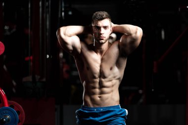 Spor salonunda güçlü duran ve kaslarını esneten yakışıklı adam - kaslı atletik vücut geliştirici spor sonrası vücut geliştirme modeli pozu