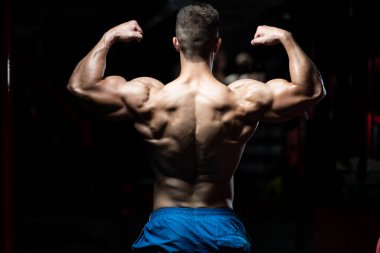 İyi eğitilmiş vücudunu gösteren genç bir adamın portresi - kaslı atletik vücut geliştirici spor sonrası vücut geliştirme modelliği pozu