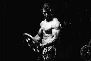 Elinde ağırlıkları olan genç bir adamın portresi.