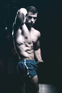 Spor salonunda güçlü duran ve kaslarını esneten yakışıklı adam - kaslı atletik vücut geliştirici spor sonrası vücut geliştirme modeli pozu