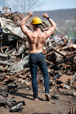 Eski Hurda Metal Garajında Güçlü Duran Genç Adam ve Esnek Kaslar - Kaslı Atletik Vücut Geliştirici Spor Modeli Sarı Miğferli Pozisyon