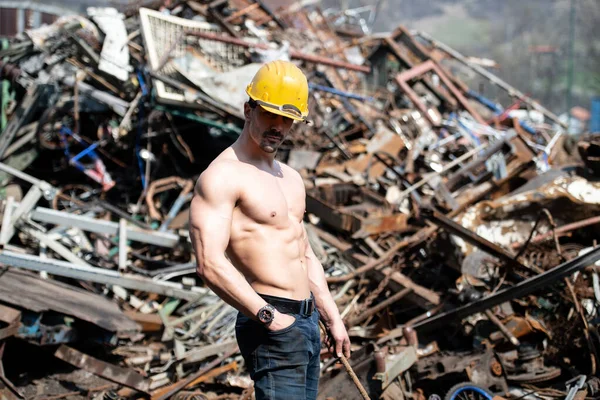 Hurdalıkta Güçlü Duran Yakışıklı Adam Endüstriyel Hurdalıkta ve Esnek Kaslarda - Kaslı Atletik Vücut Geliştirici Sarı Miğferli Fitness Pozisyonu